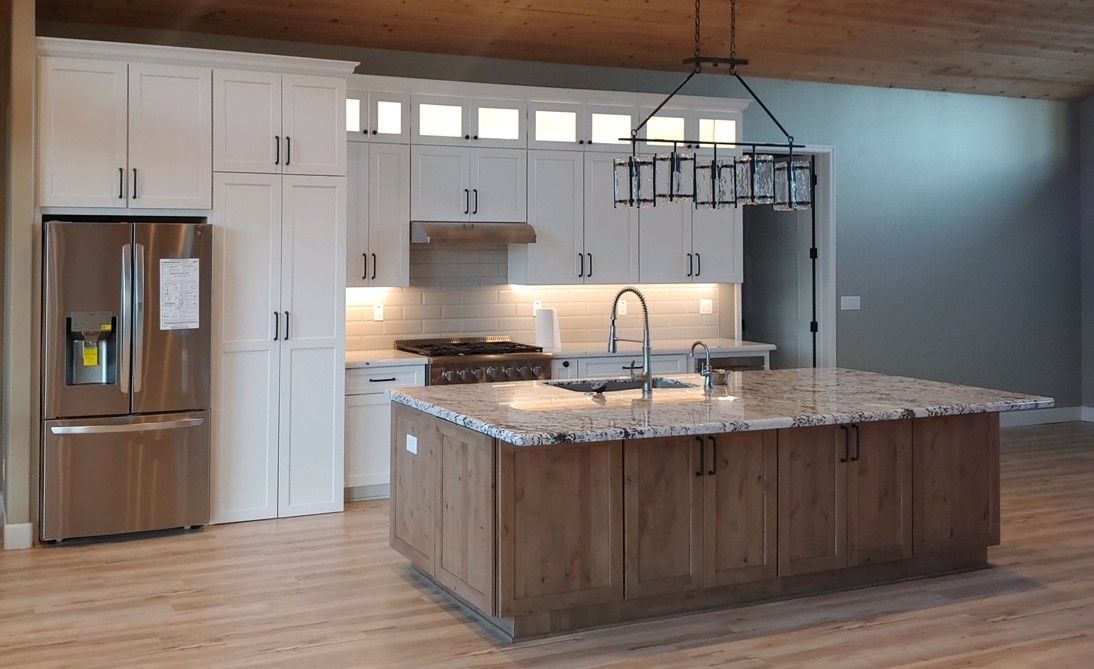 Modern kitchen with white cabinets, stainless steel refrigerator, and wooden island.