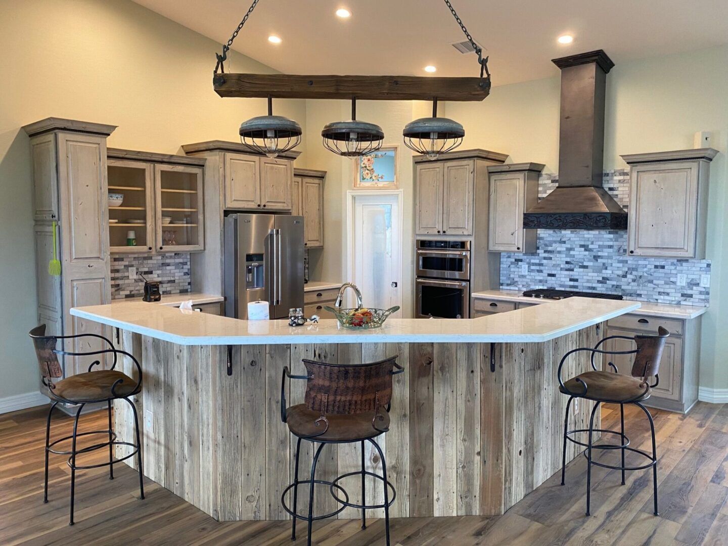 Kitchen with a rustic wood island and light-colored cabinets. Includes a stove hood and hanging pendant lights.