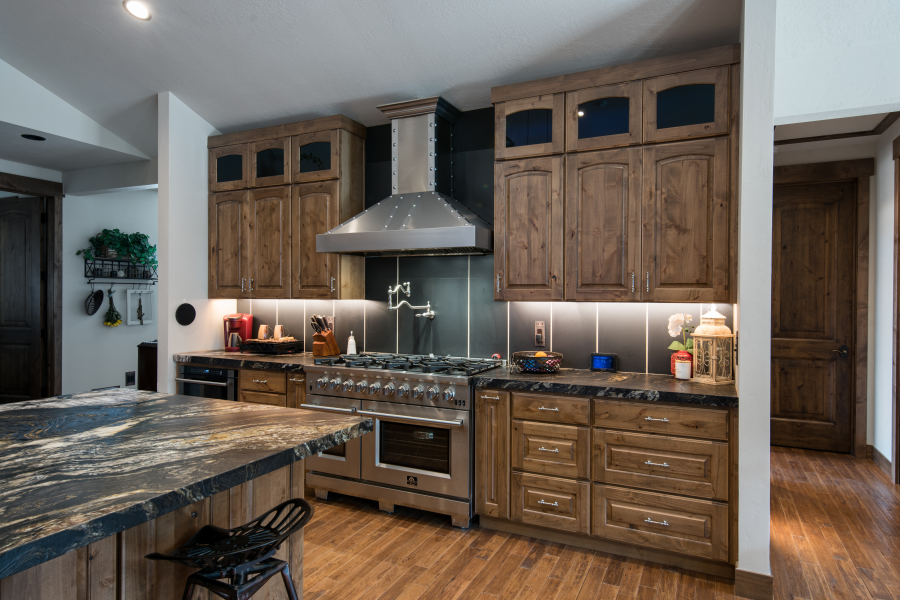 Rustic kitchen with wooden cabinets, stainless steel range hood, and granite countertops.