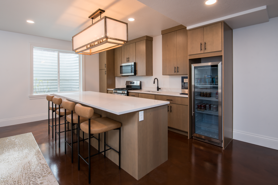 Modern kitchen with island, seating, cabinets, and a beverage cooler.