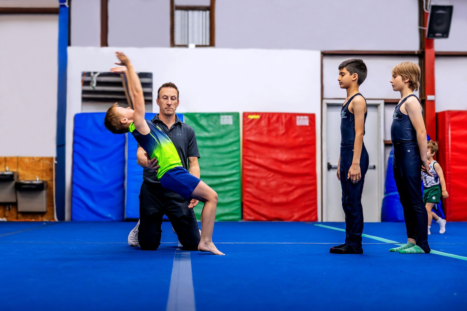 A group of young boys are practicing gymnastics in a gym.