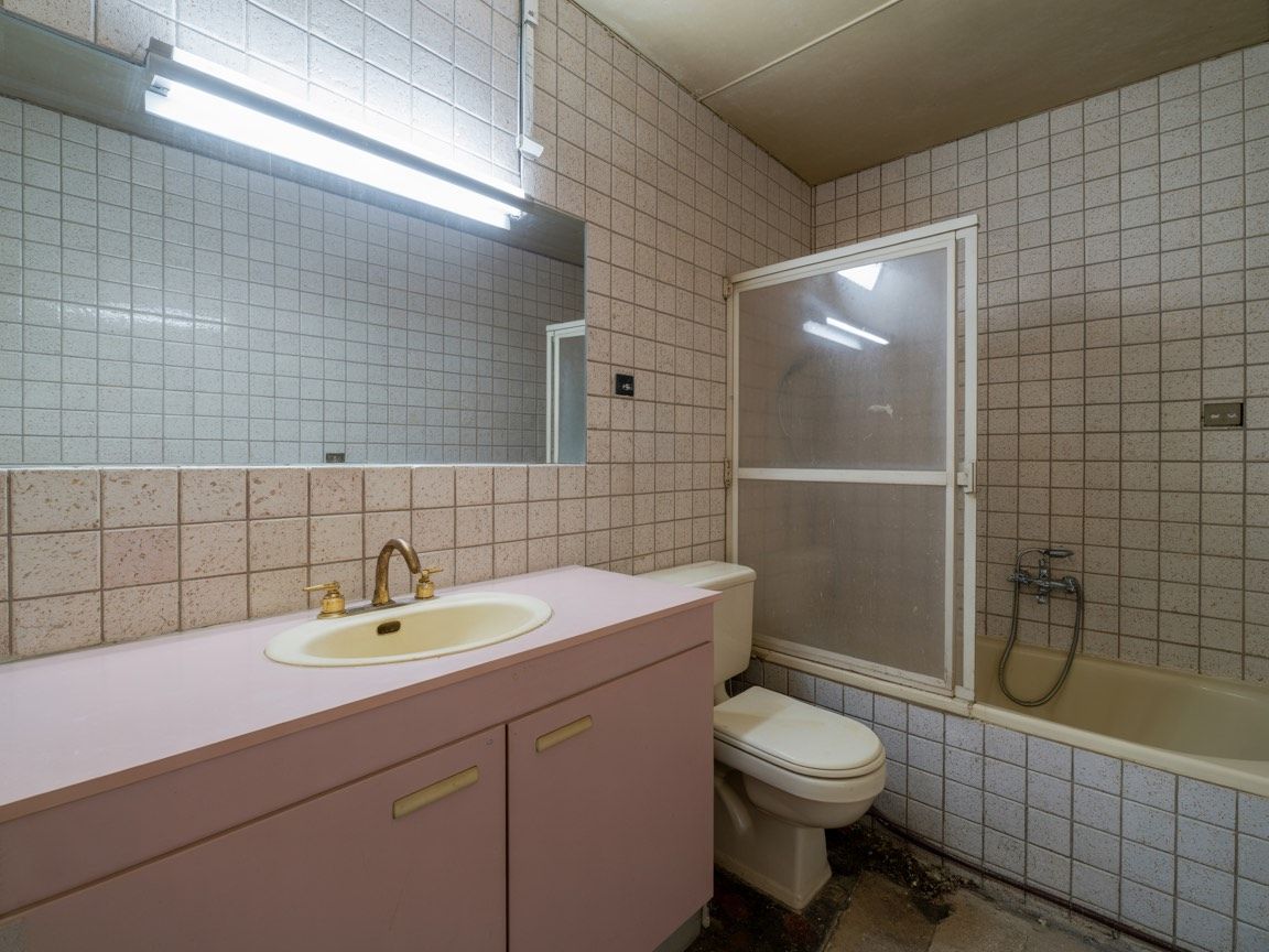 Modern white kitchen with marble countertops, wood floors, and globe pendant lights.