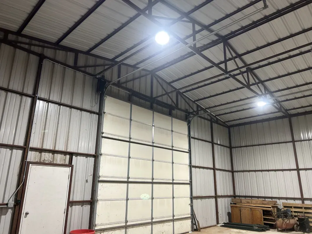 Interior of a metal warehouse with a large door and two overhead lights.