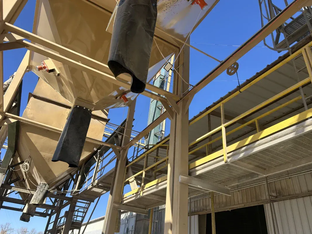 Industrial equipment, beige metal framework, chute with gray fabric, blue sky.