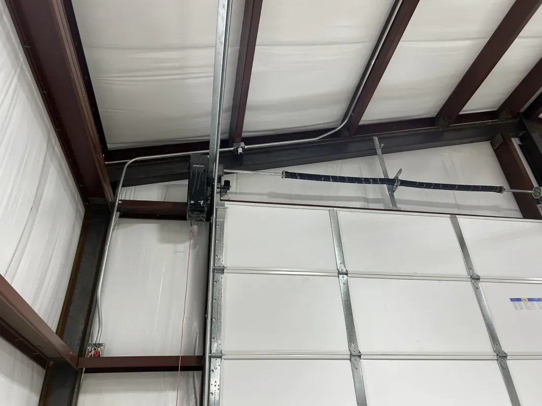 Interior view of a garage with a steel beam frame, insulated walls, and a garage door.