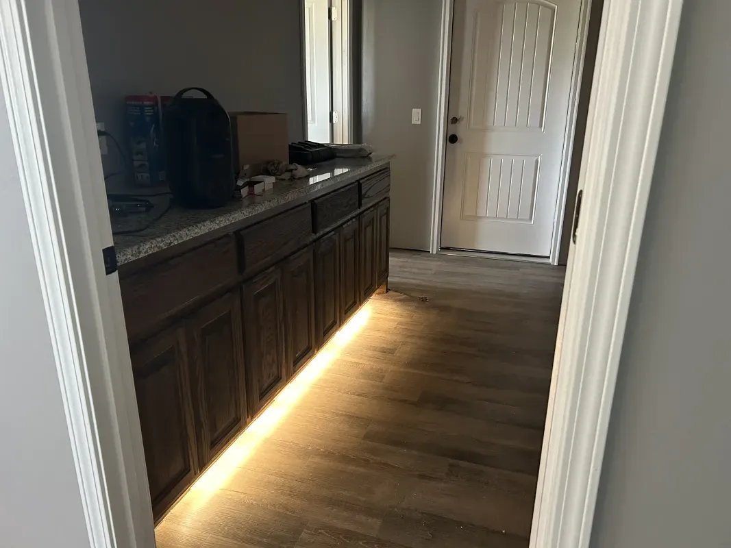 Cabinet with under-cabinet lighting in a room. Door and counter in background.