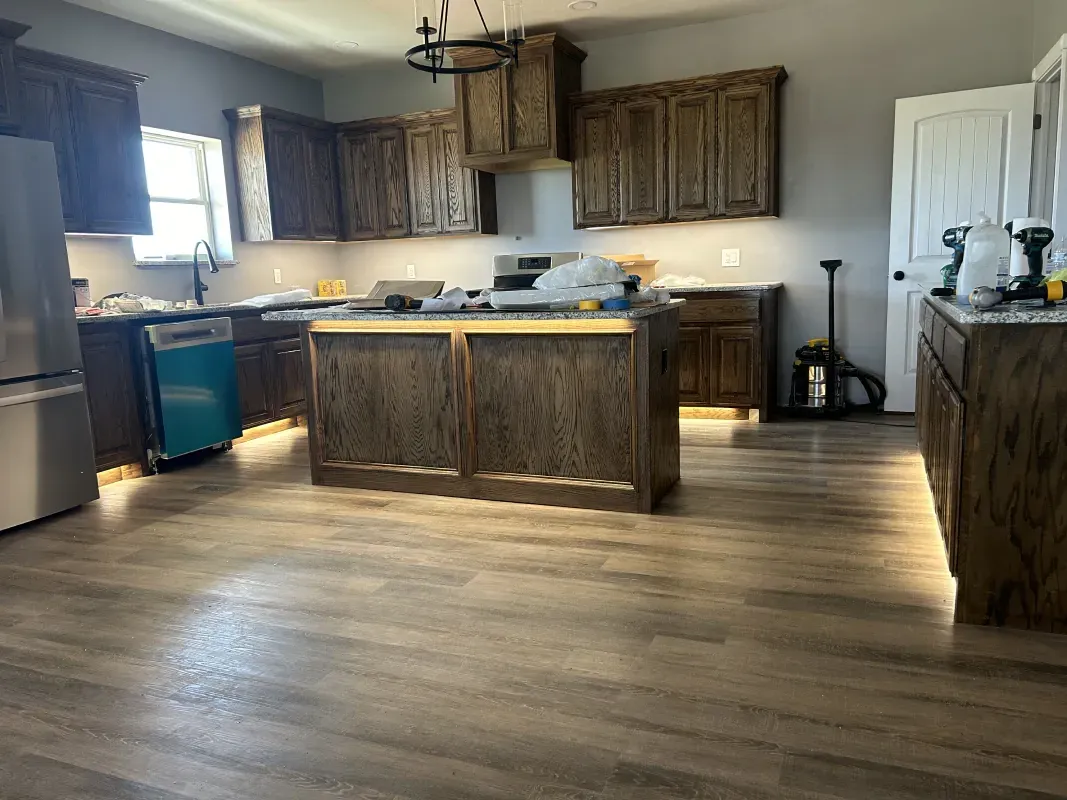Kitchen with dark brown cabinets, an island, and gray flooring; partially completed.