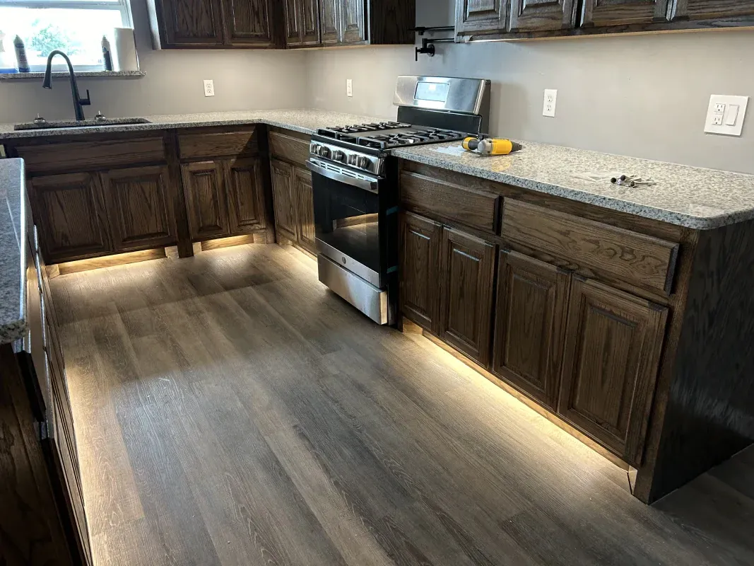 A kitchen with wood cabinets, granite countertops, and under-cabinet lighting.