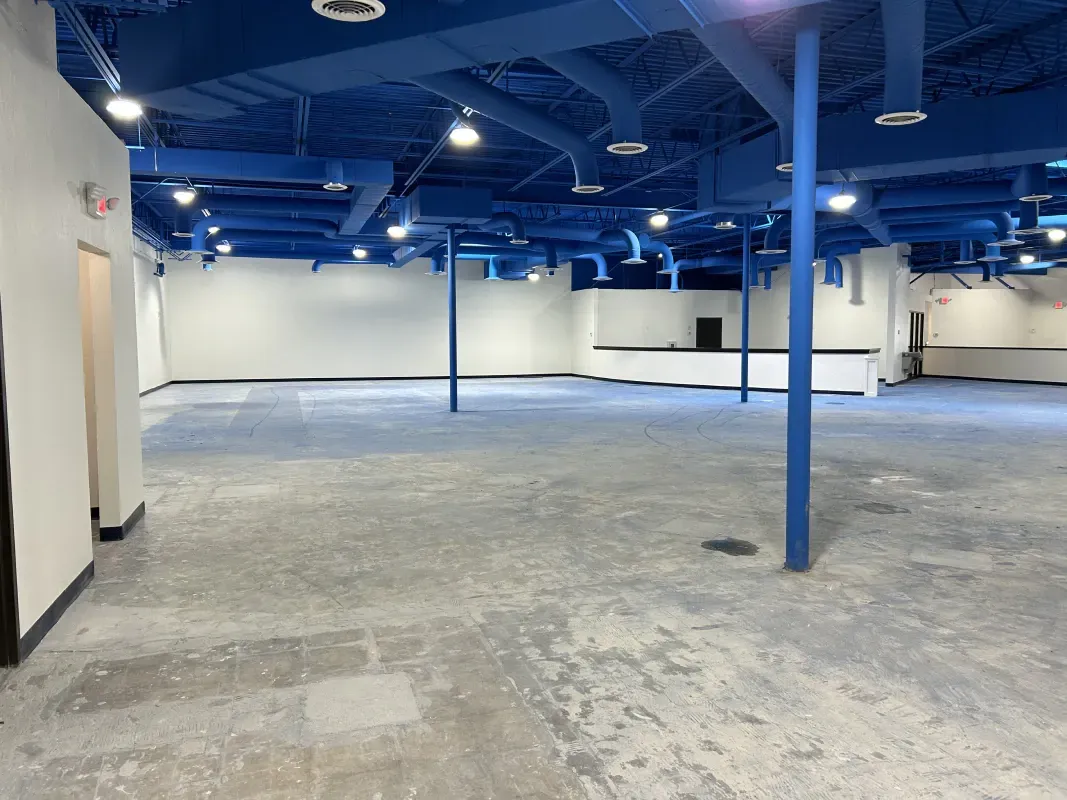 Empty commercial space; blue ceiling, gray floor, white walls.