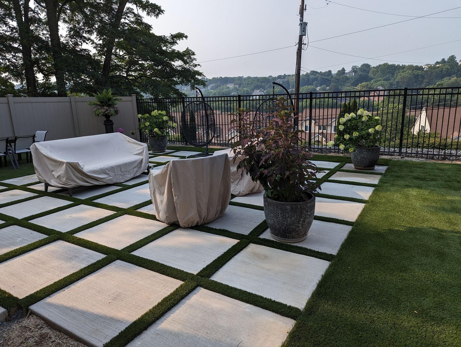 Brown house with black mulch landscaping, green grass, and small plants.