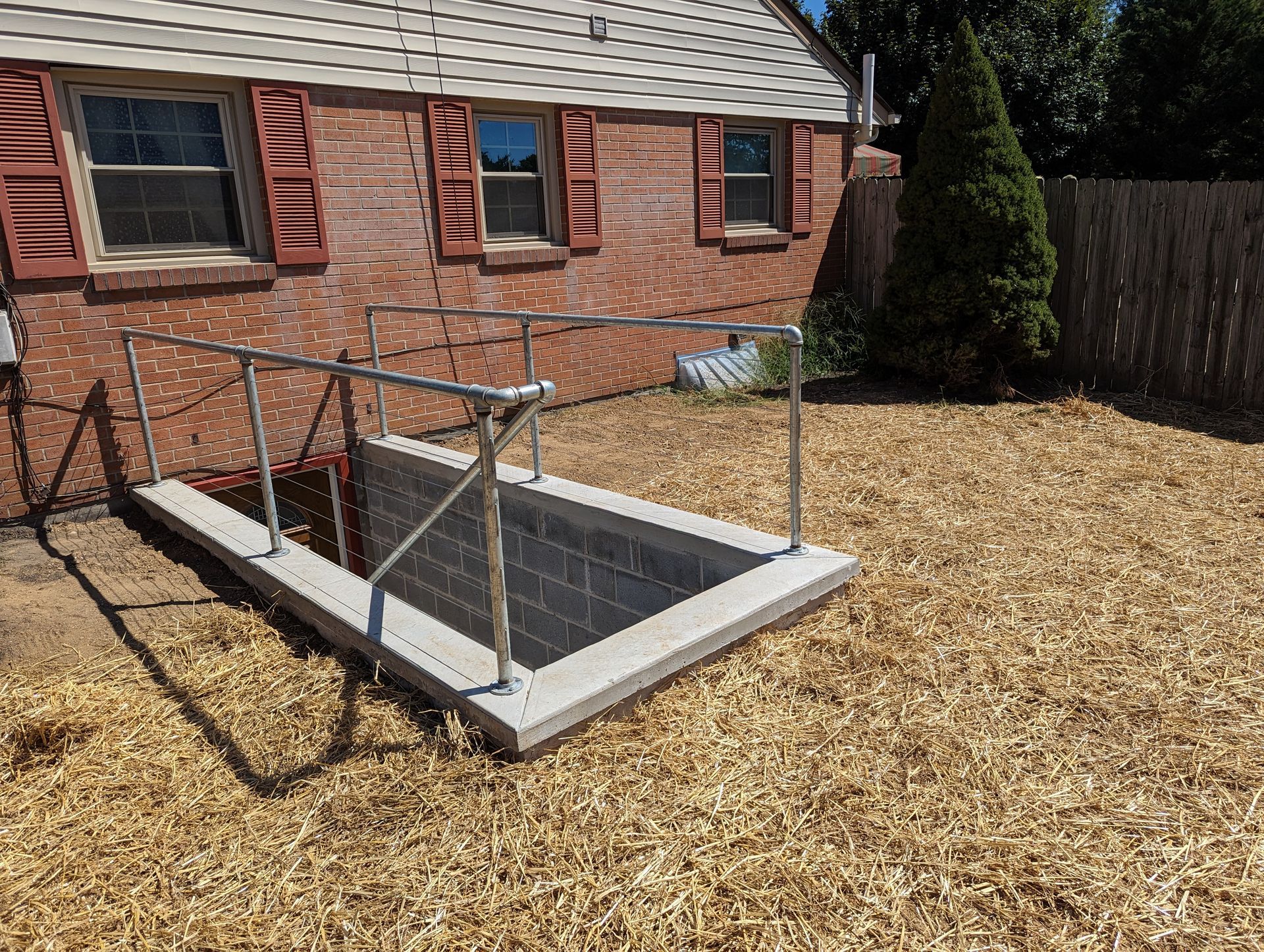 Brick building with a concrete and brick entryway, metal railings, and wood-chip ground.