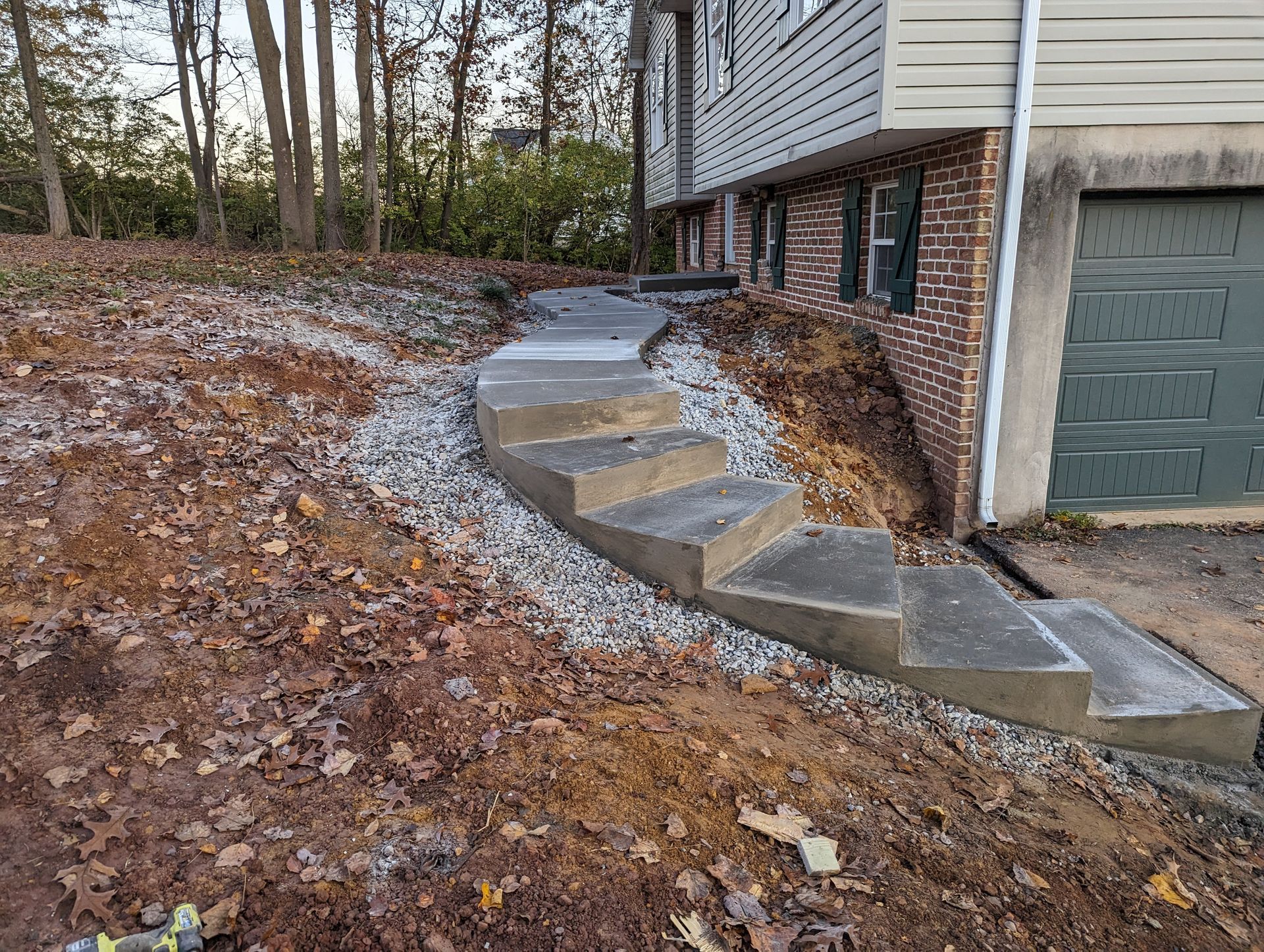 Concrete steps leading up a sloped yard to a house with a garage. 