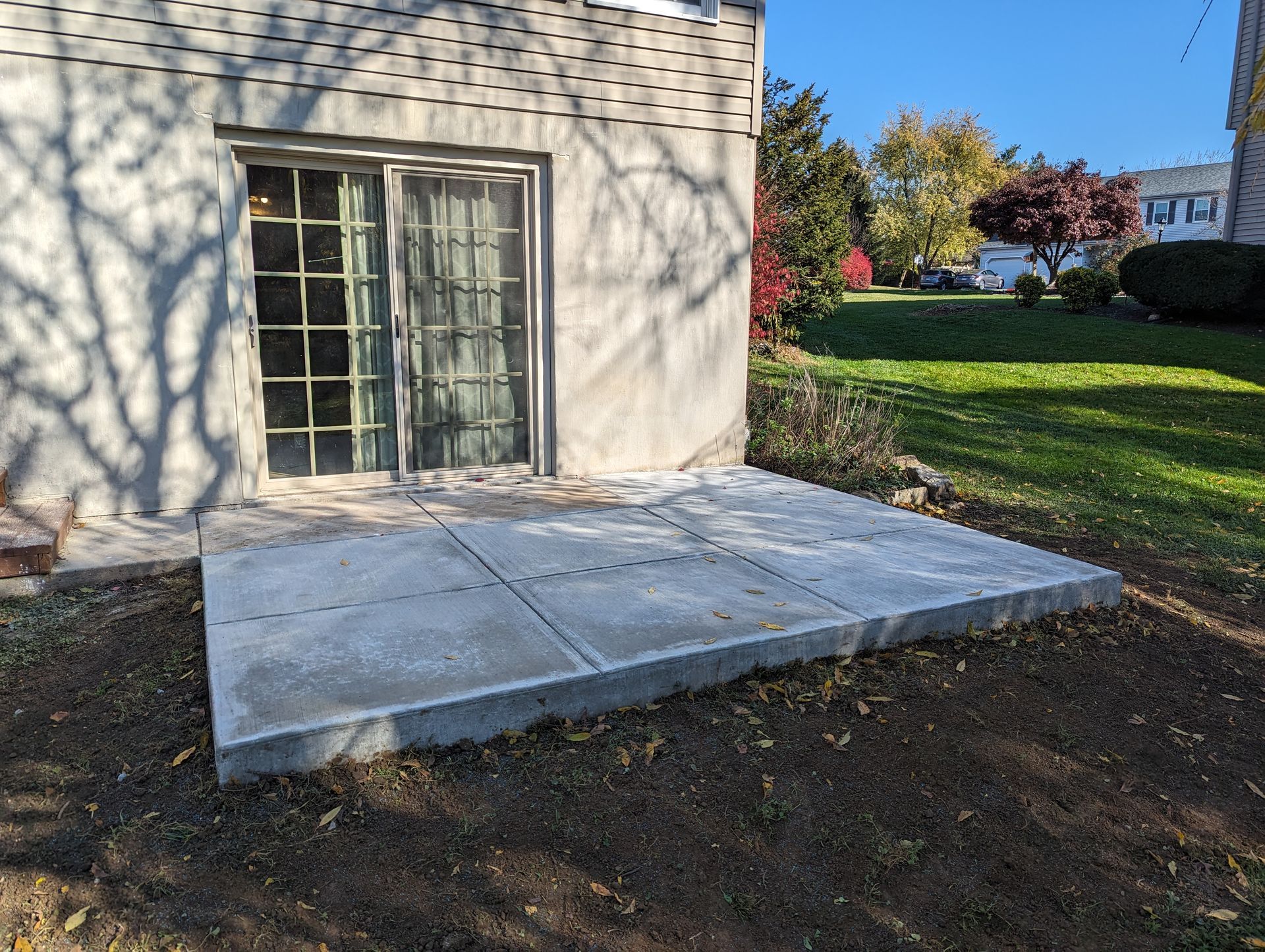 Concrete patio outside a building with a sliding glass door.