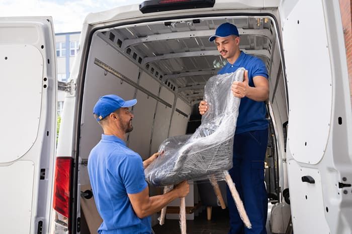 Two Men Loading a Chair Into the Back of A Van — Town & Country Removals In Camden Haven, NSW