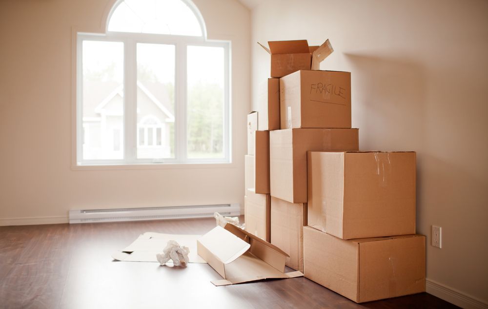A Bunch of Cardboard Boxes Are Stacked on Top of Each Other in An Empty Room  — Town & Country Removals In Wauchope, NSW