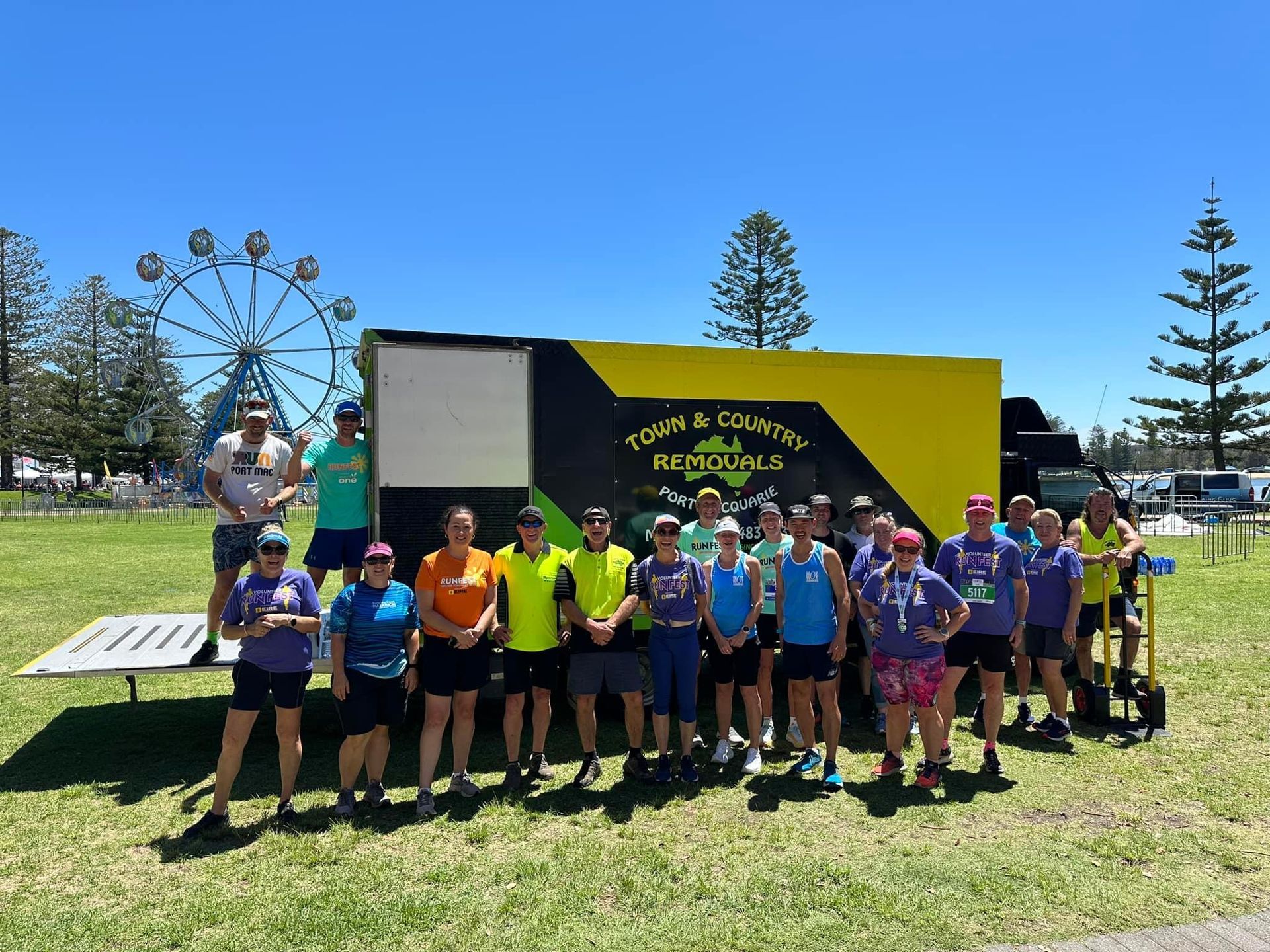 A Moving Truck Parked on Grass with a Group of People Standing in front  — Town & Country Removals In Port Macquarie, NSW