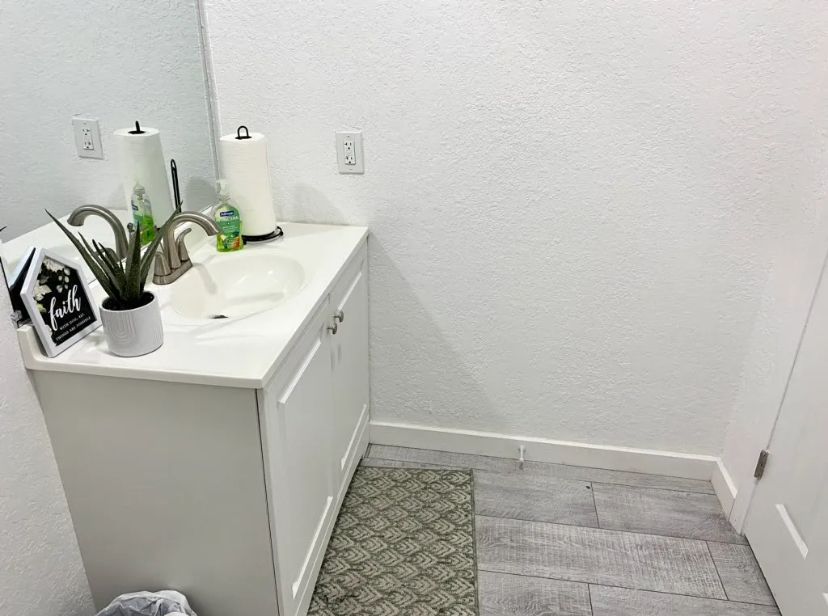 A bathroom with a sink , mirror and trash can. BEFORE/AFTER