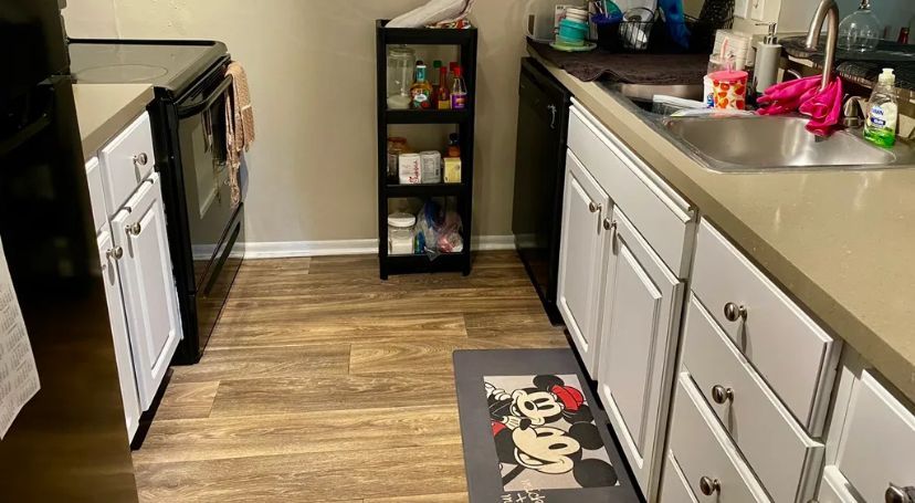 A kitchen with white cabinets , a sink , a stove , and a rug on the floor.
BEFORE/AFTER