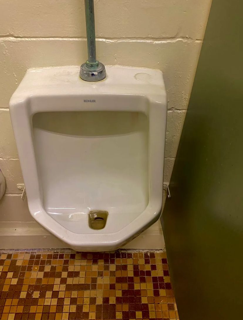 A urinal in a public restroom with a mosaic floor. BEFORE/AFTER