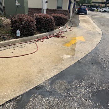 A hose is being used to clean the sidewalk outside of a building. BEFORE/AFTER