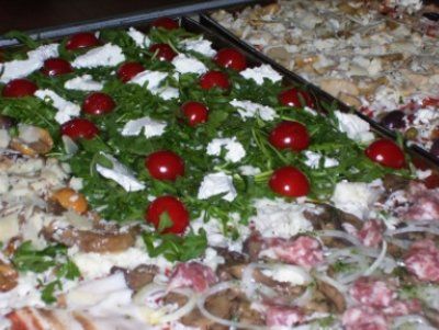 a pizza ready to bake in a pan with rocket leaves, cherry tomatoes and other ingredients