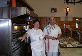 a woman and a man in aprons by the oven