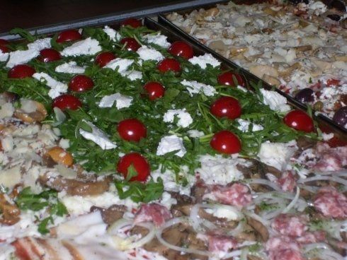 una pizza pronta da infornare in una teglia con rucola pomodorini e altri ingredienti