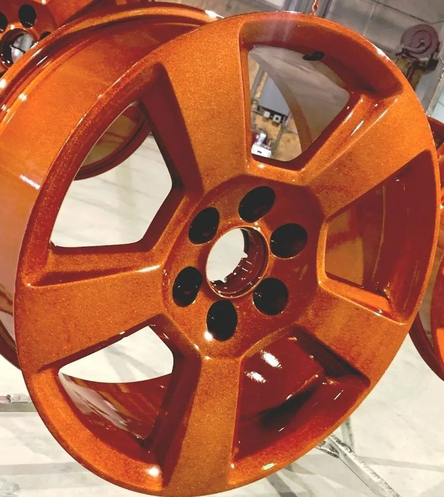 Orange-colored car rim with a textured finish and five spokes.