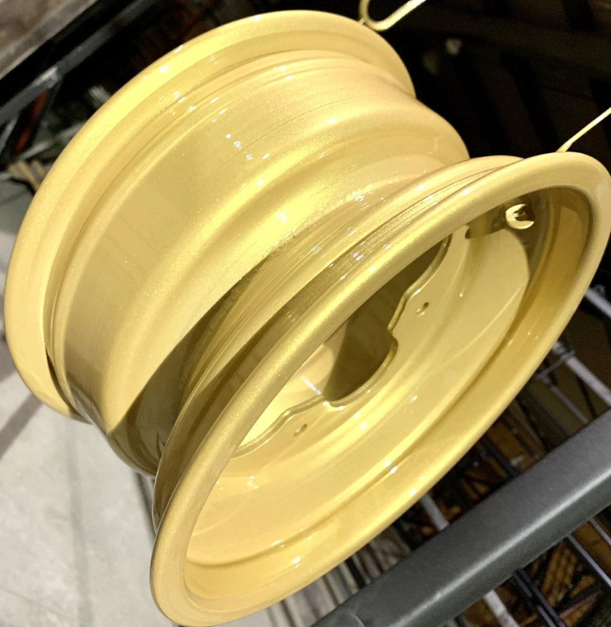 Gold-painted car wheel, hanging on a rack.