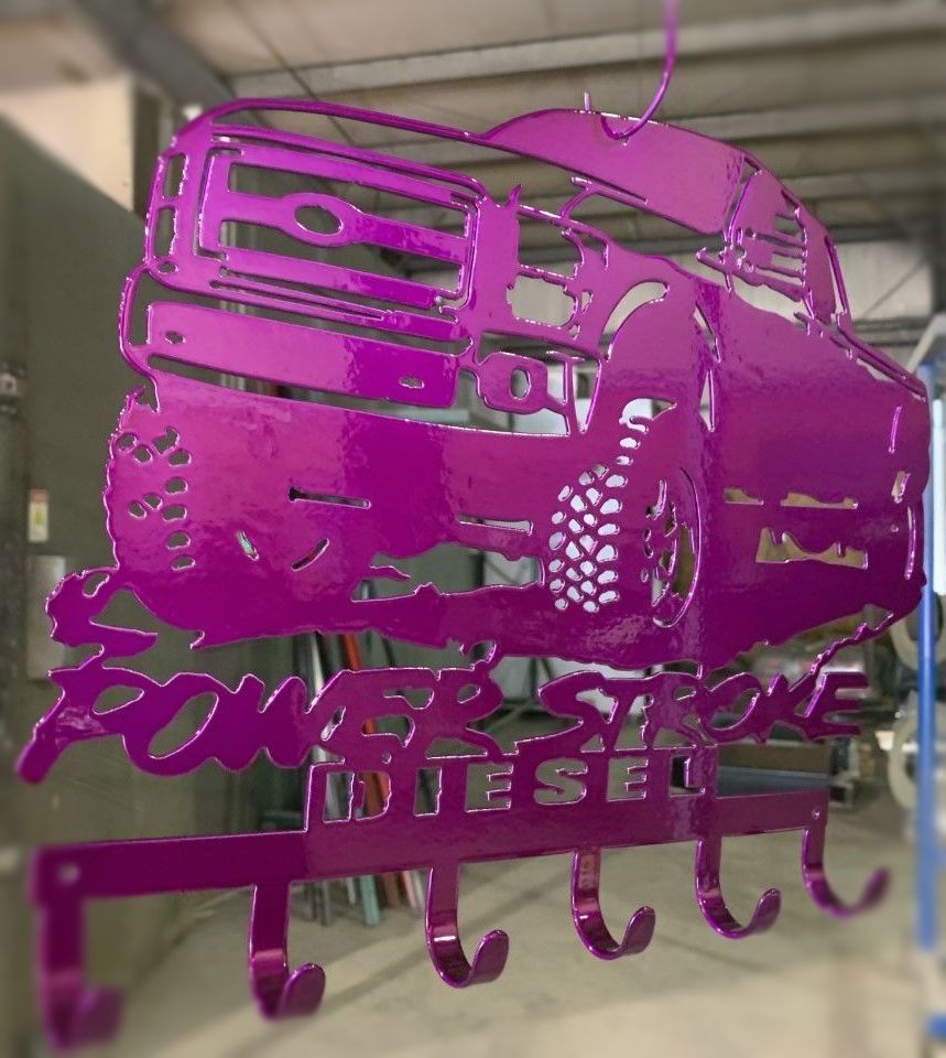 Pink metal art piece shaped like a Ford truck with hooks for keys, reading