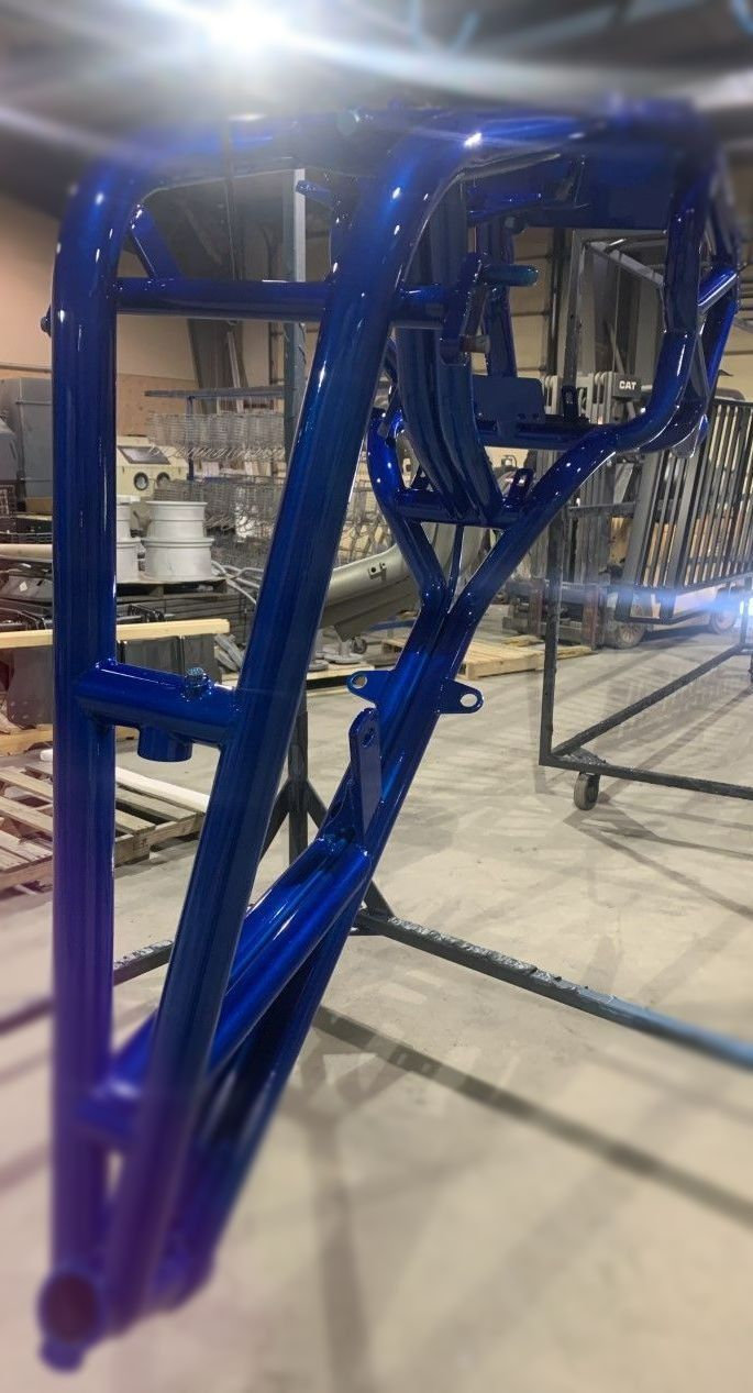 Blue painted motorcycle frame in an industrial setting.