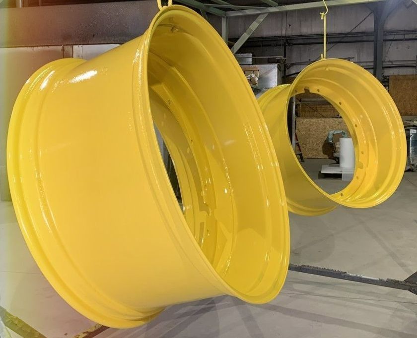 Two yellow tractor rims hanging in a workshop.