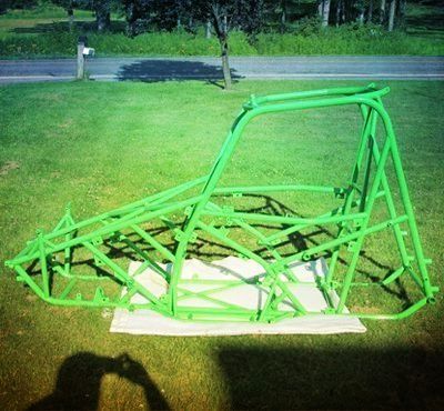 Green buggy frame on a lawn, shadow of person taking photo.