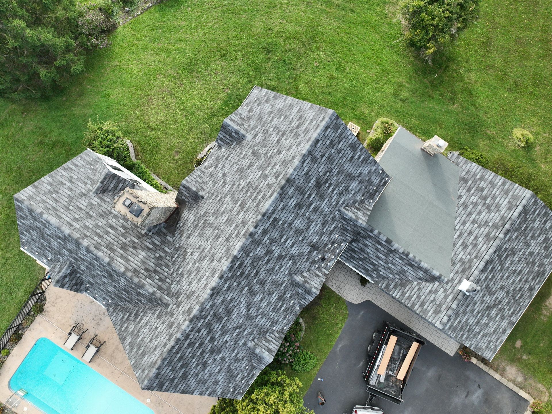 A top aerial view of a house with a custom asphalt roof replacement