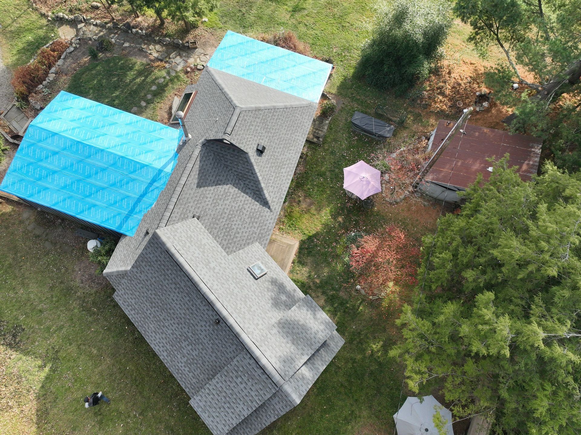An aerial view of a house with a blue tarp on the roof.