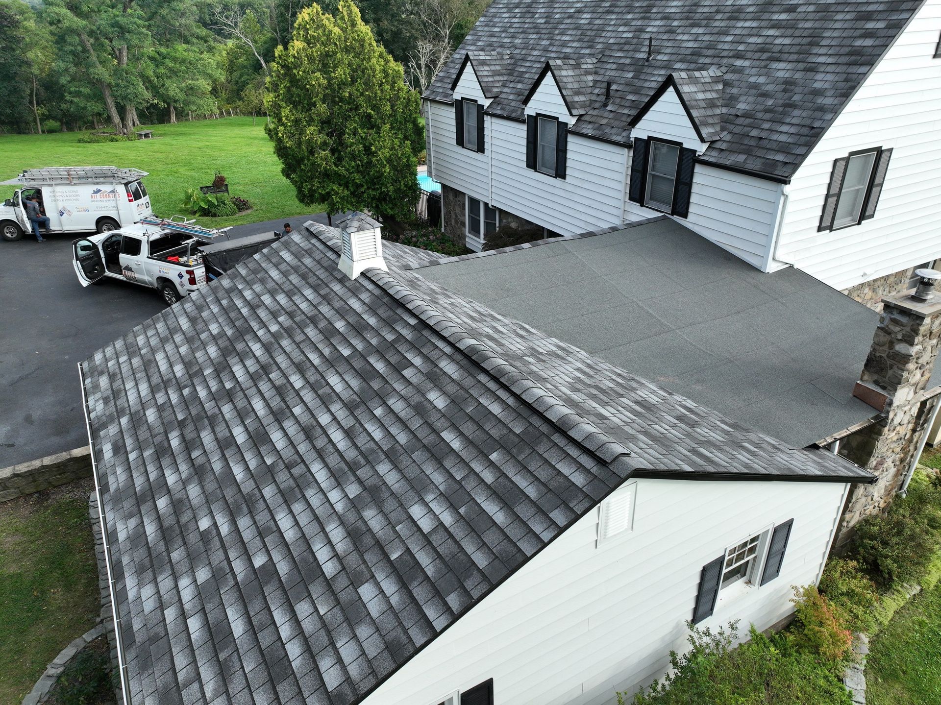 An aerial view of a house with a roof replacement with custom asphalt shingles