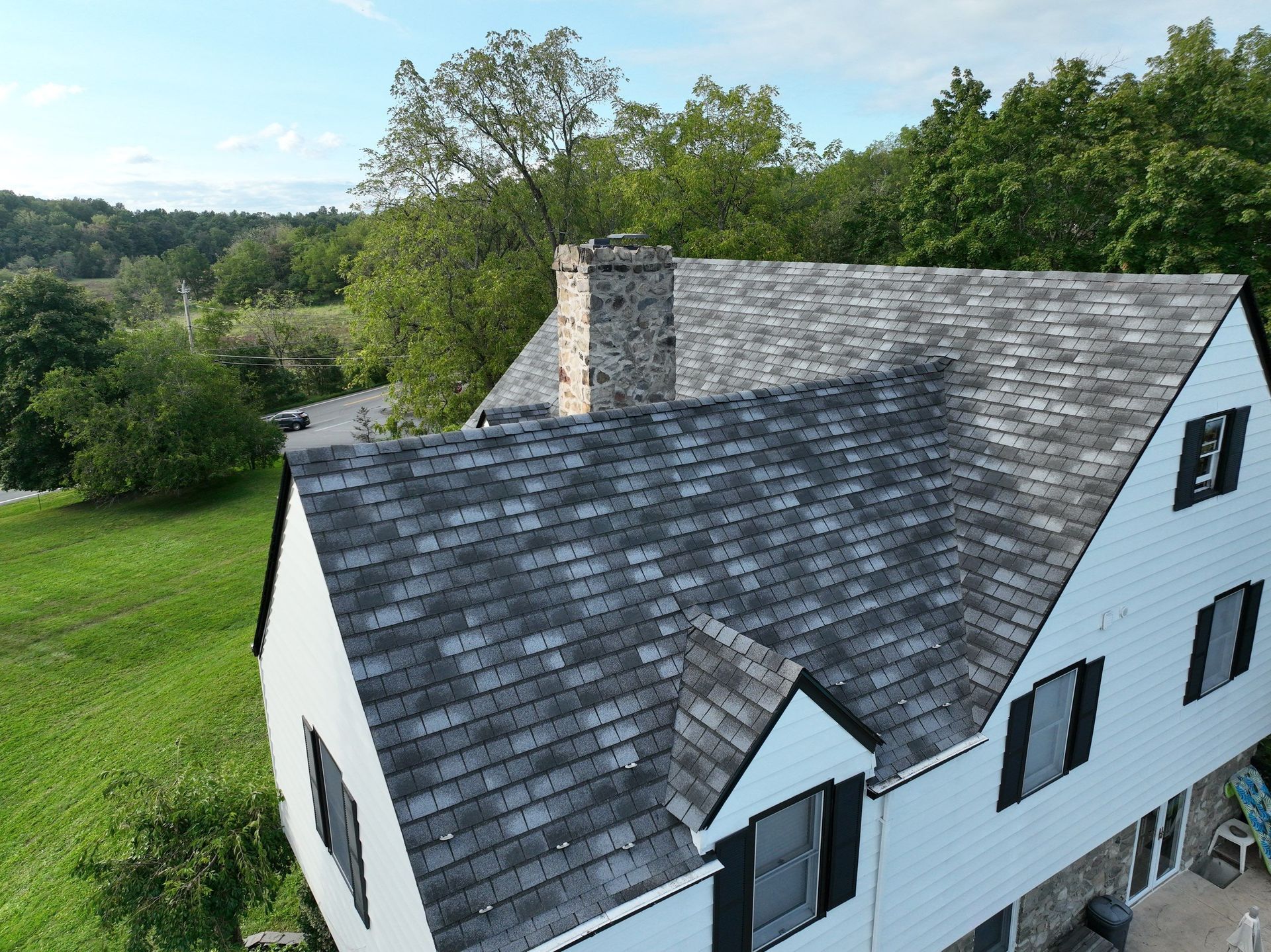 An aerial view of a white house with a gray roof
