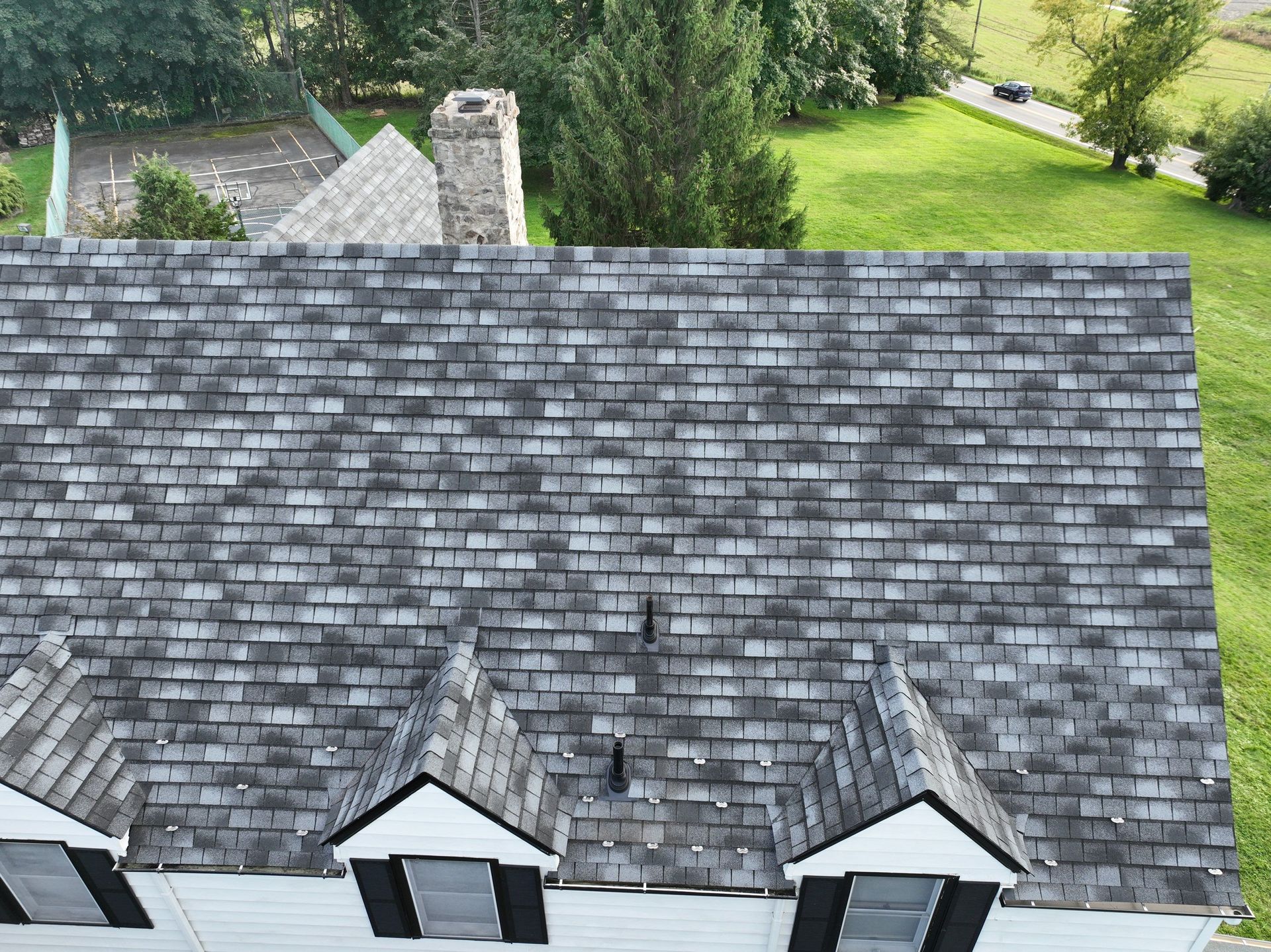 An aerial view of a house with a gray and variety colored roof installation