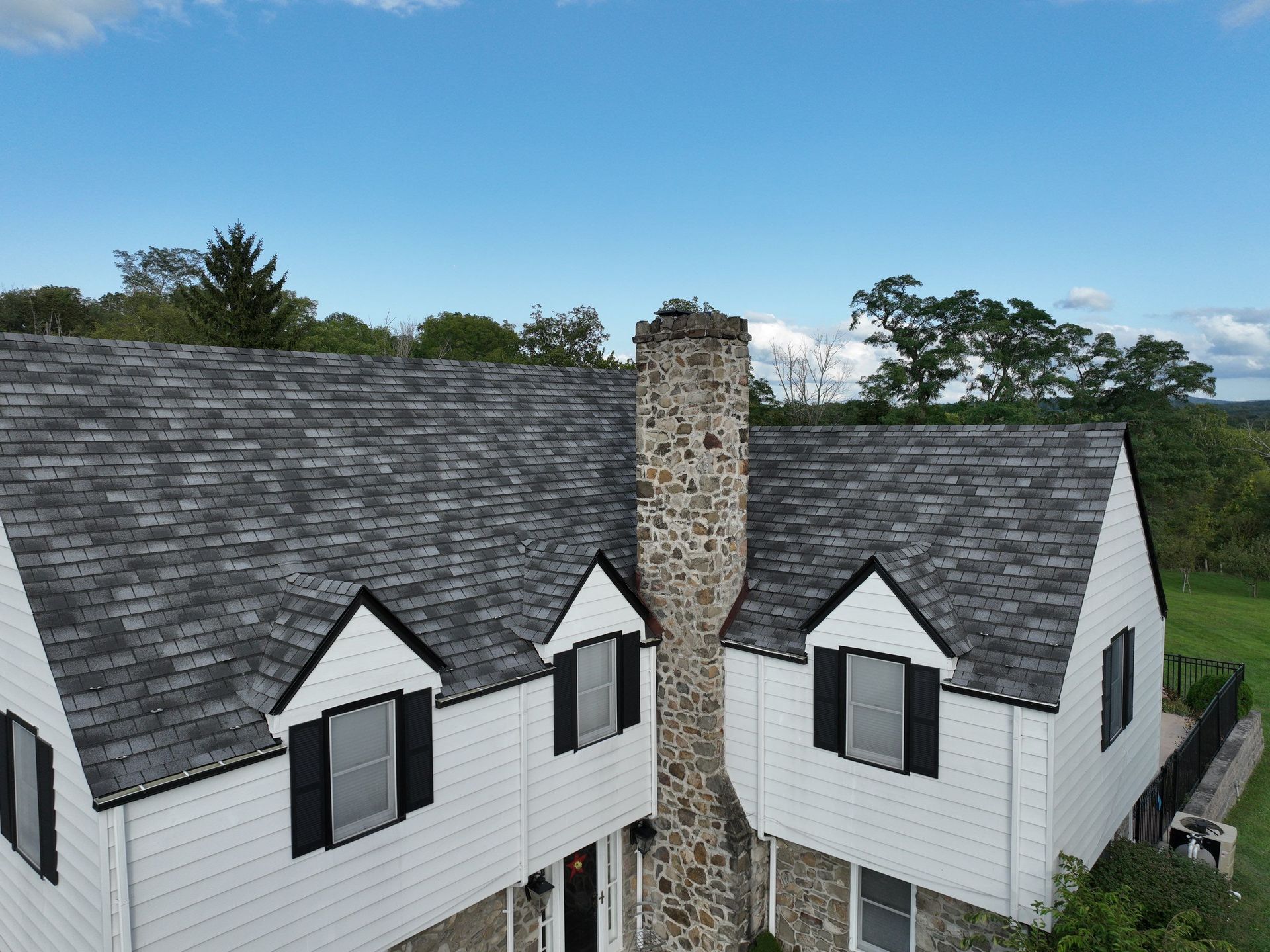 An aerial view of a white house with a black roof