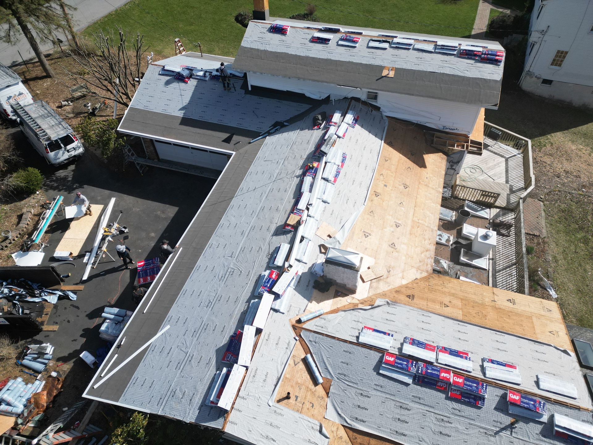 An aerial view of a roof being installed on a house with GAF shingles