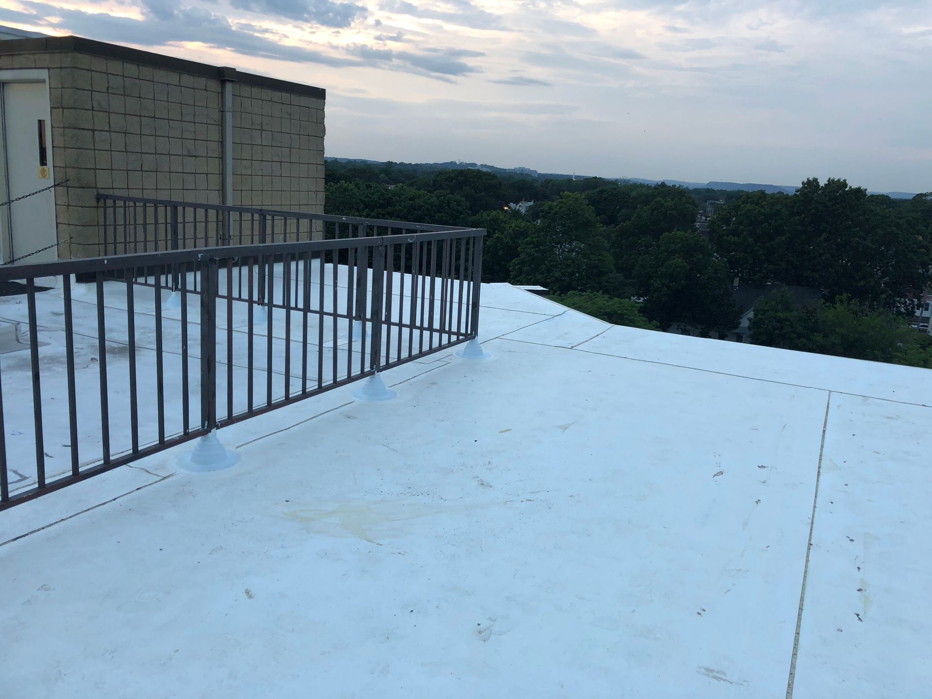A white roof with a metal railing on top of it.