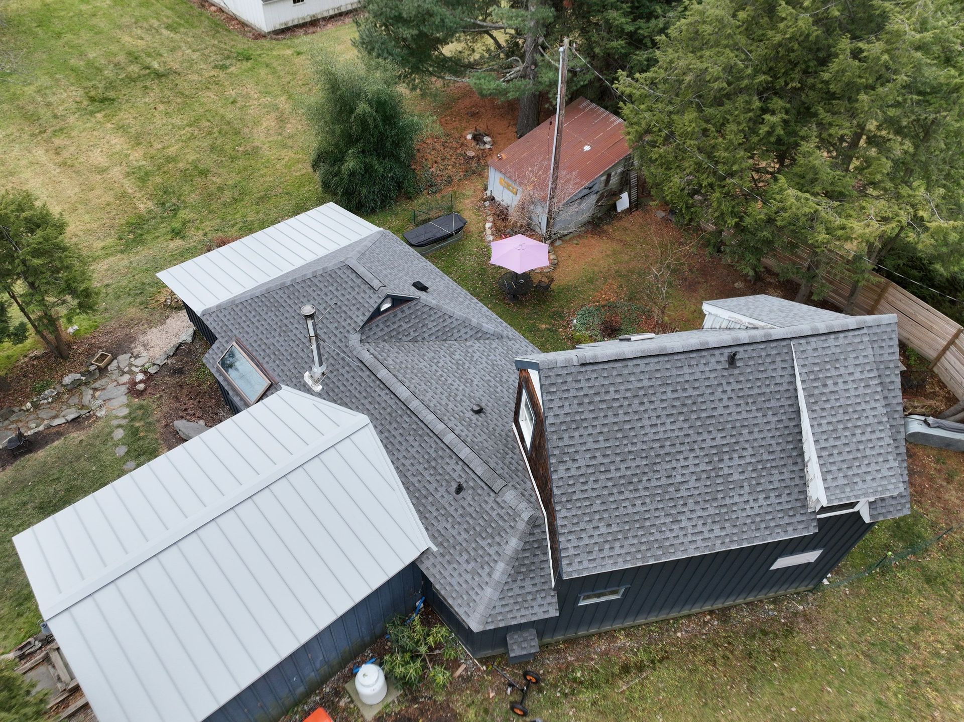 An aerial view of a house with a metal and asphalt roof replacement