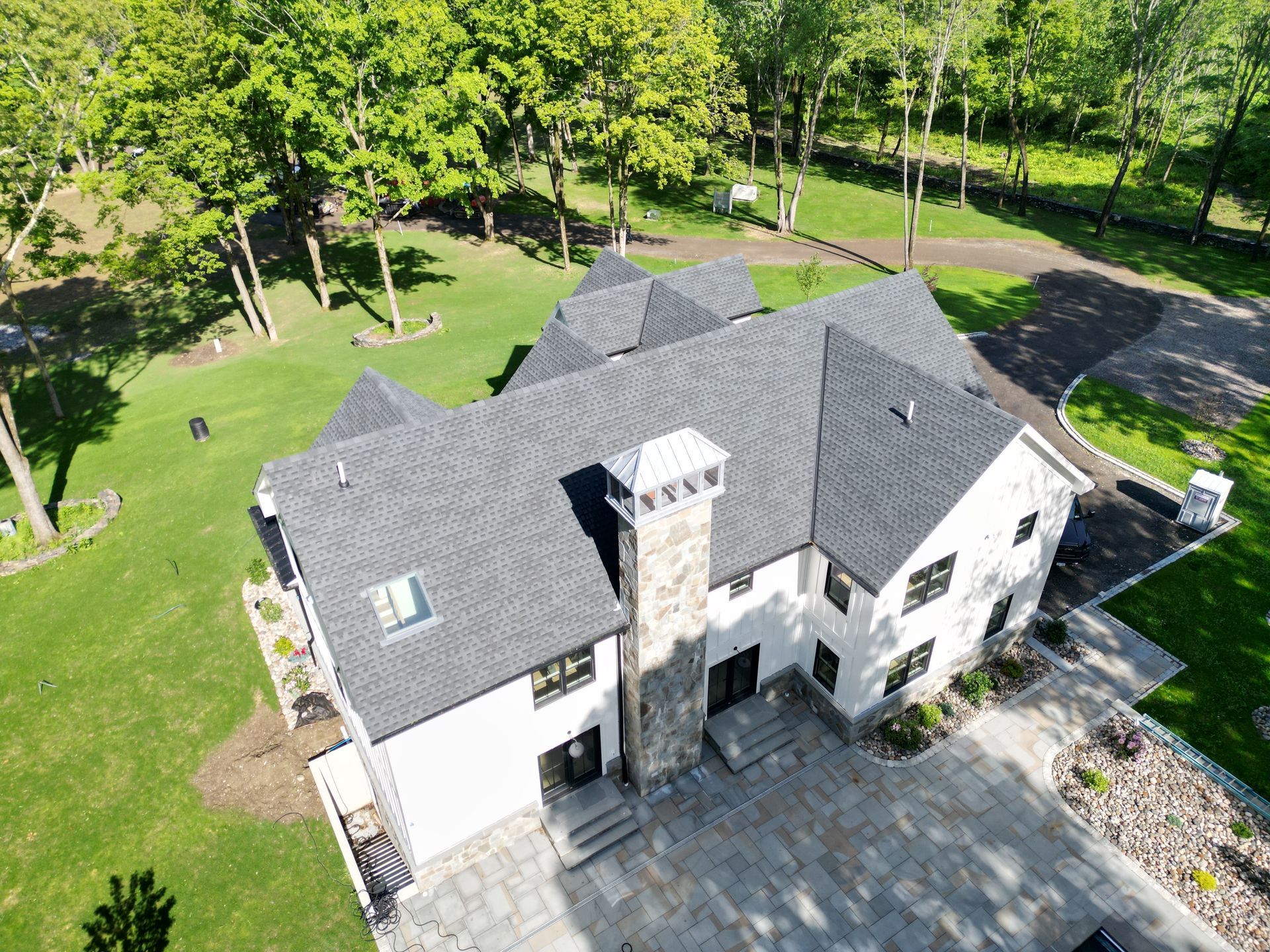 An aerial view of a large white house with a black roof replacement
