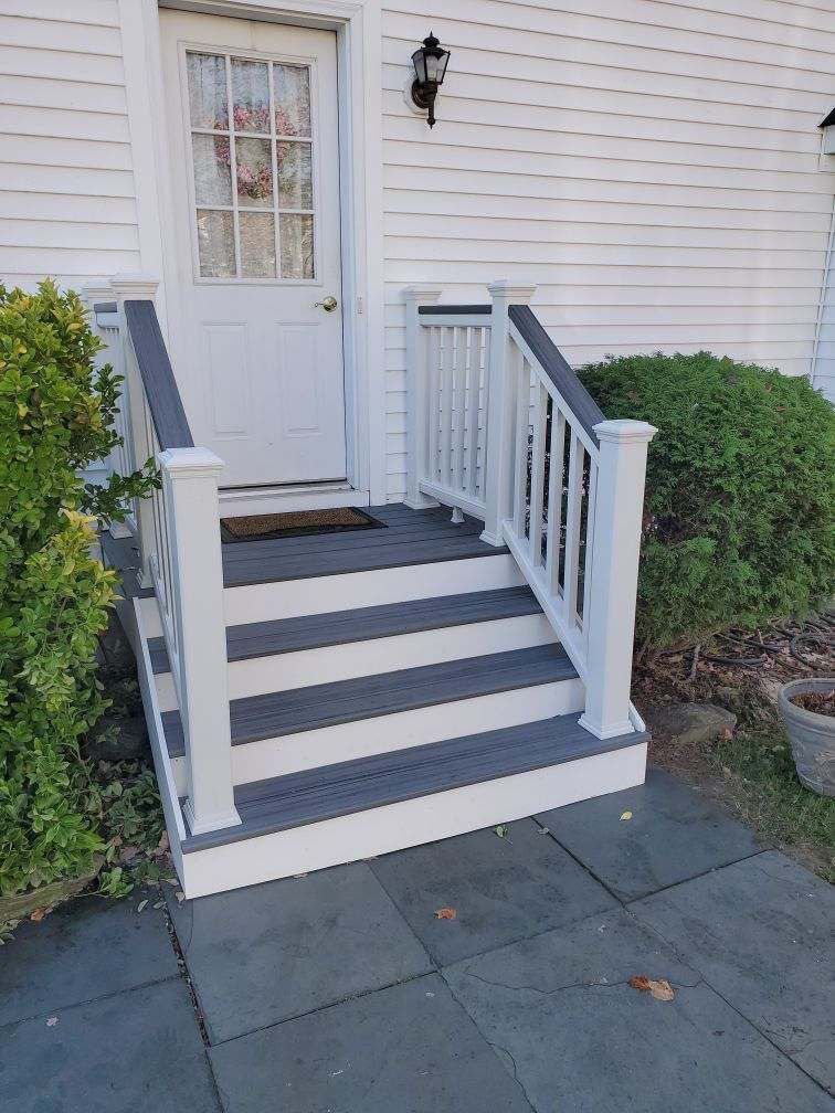 A white house with stairs leading up to the front door.