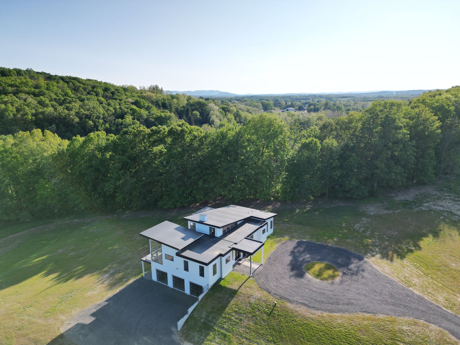 An aerial view of a house in the middle of a field surrounded by trees.