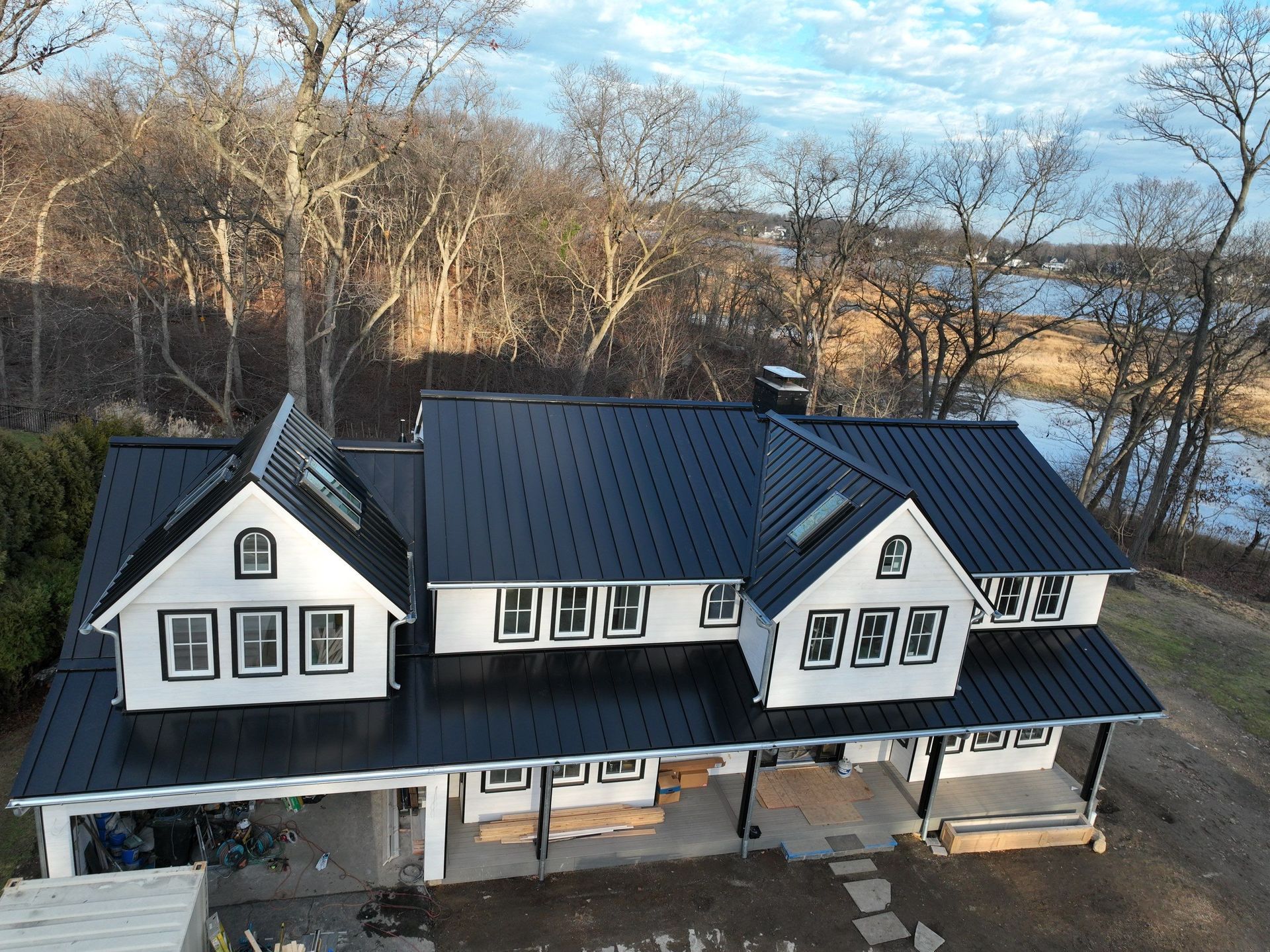 Front view of a large white house with a black metal roof installation
