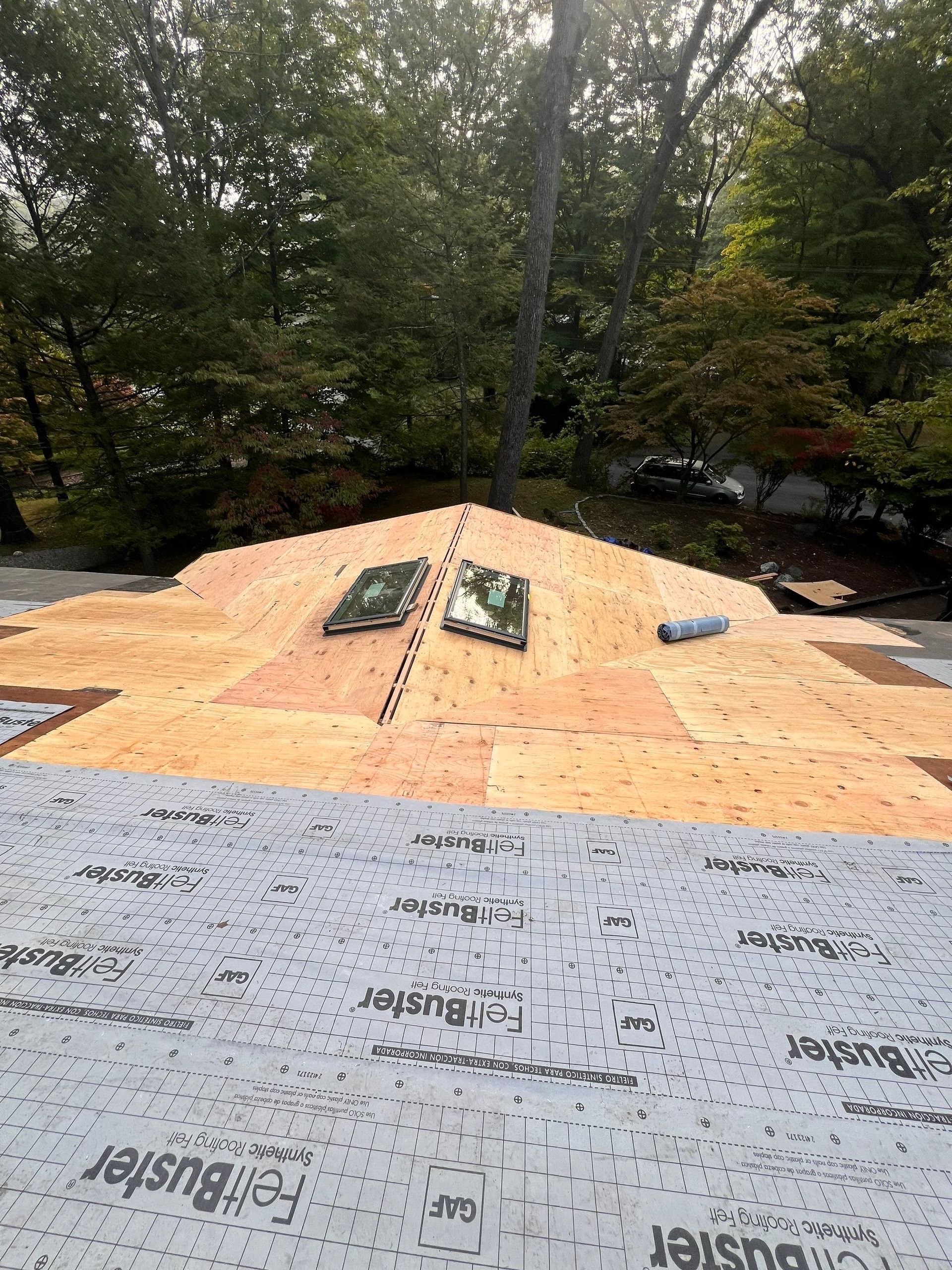 The roof of a house is being built and there are two skylights on the roof.