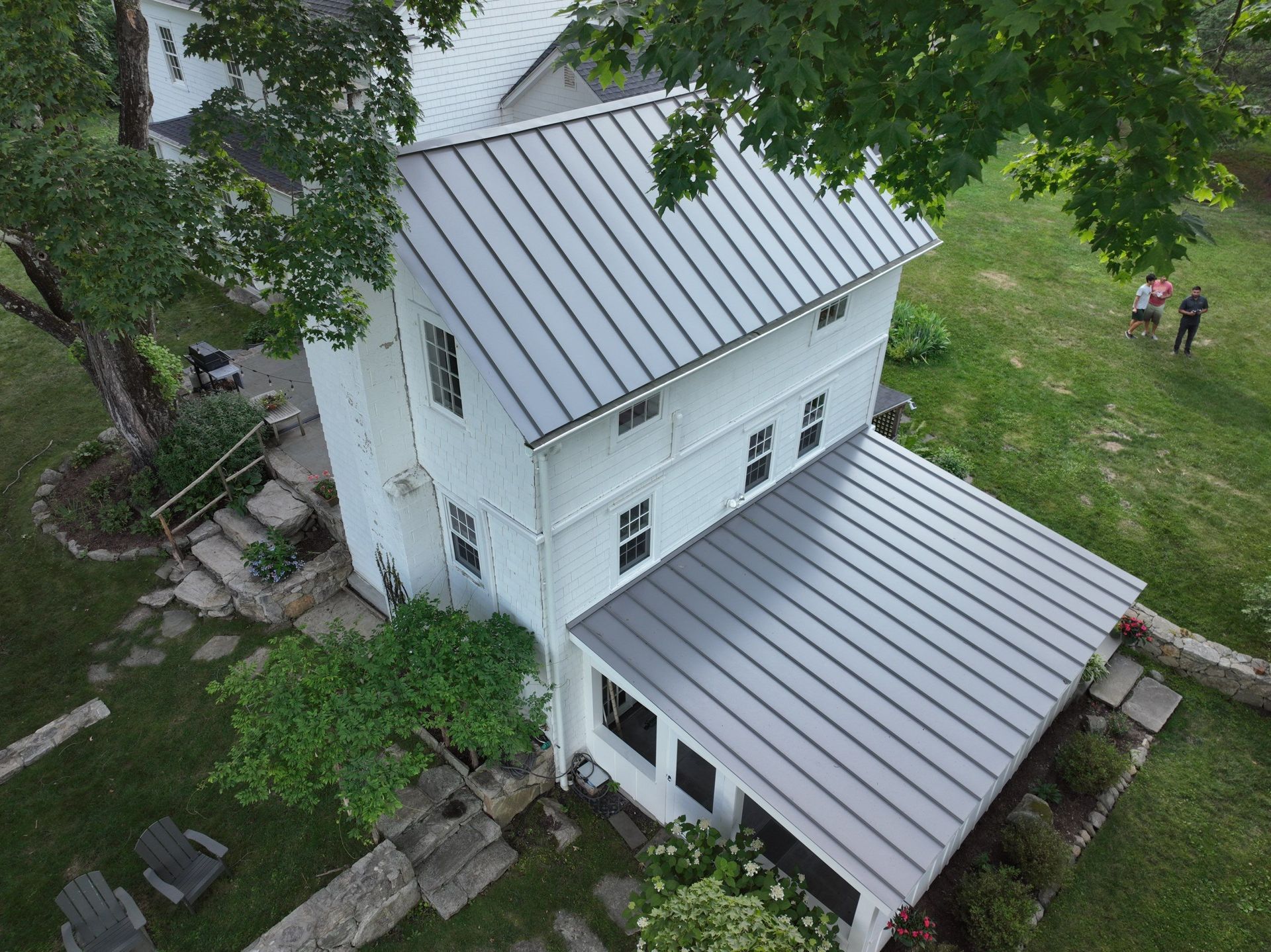 An aerial view of a white house with a metal roof.