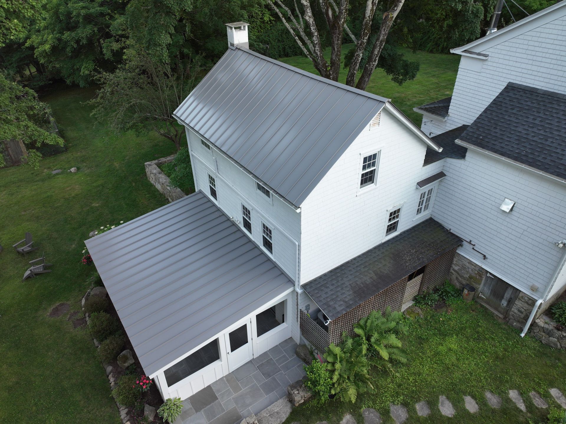 An aerial view of a white house with a gray metal roof installation