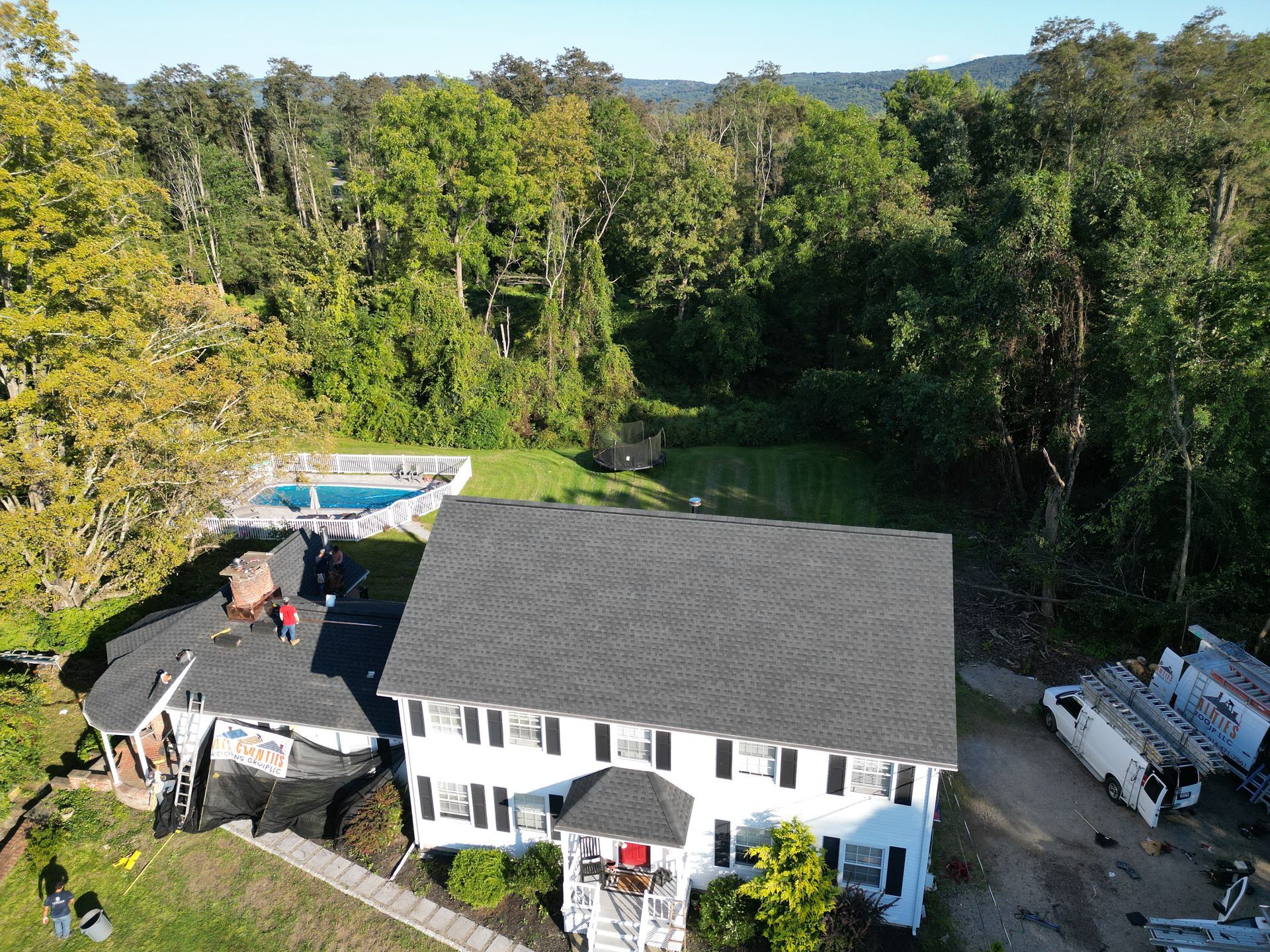 An aerial view of a large white house with a new dark roof